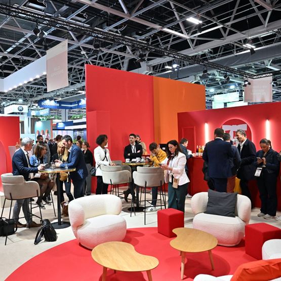 Professionals networking at a B2B trade show in a colorful and stylish lounge area, enjoying a friendly atmosphere.